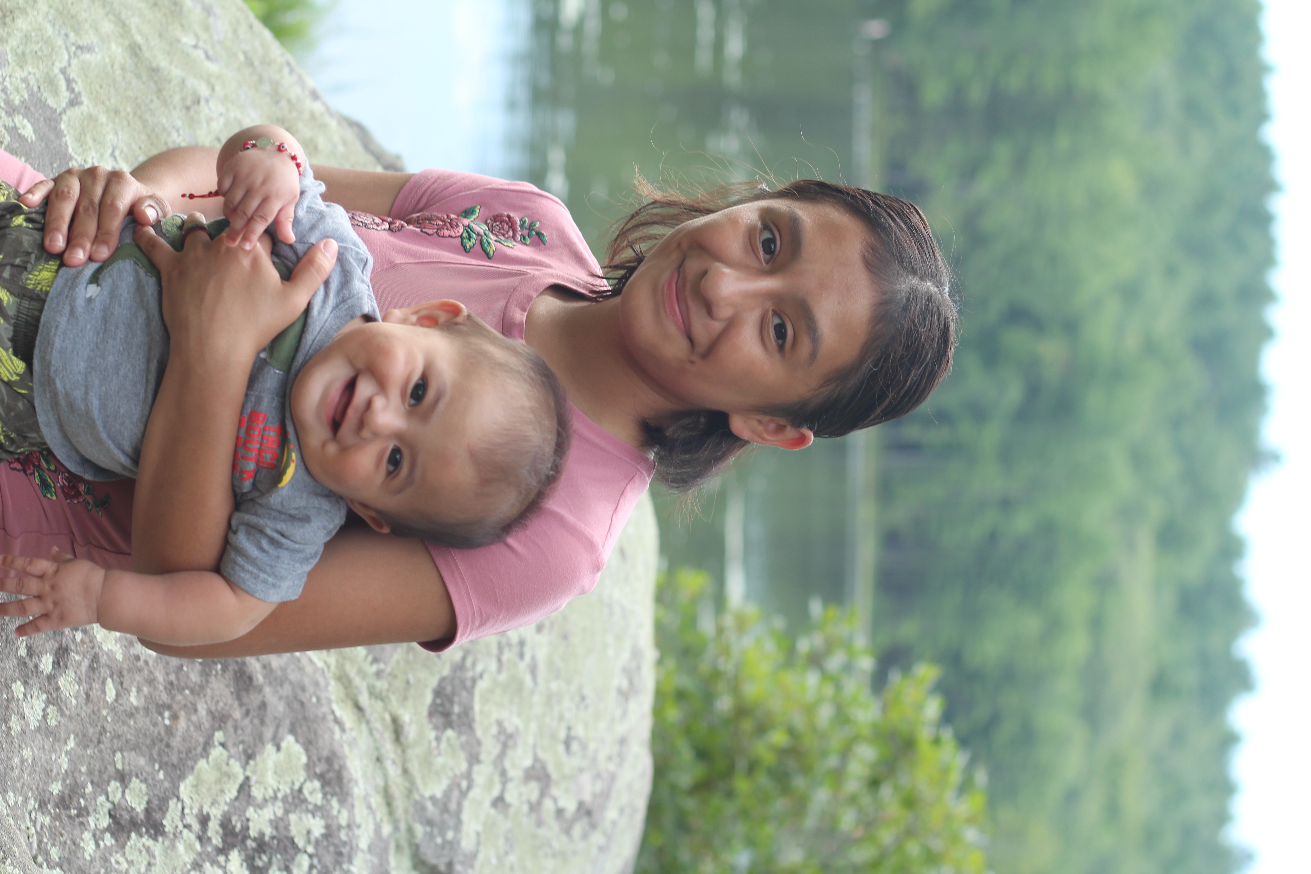 A teen mom laughing with her baby outdoors